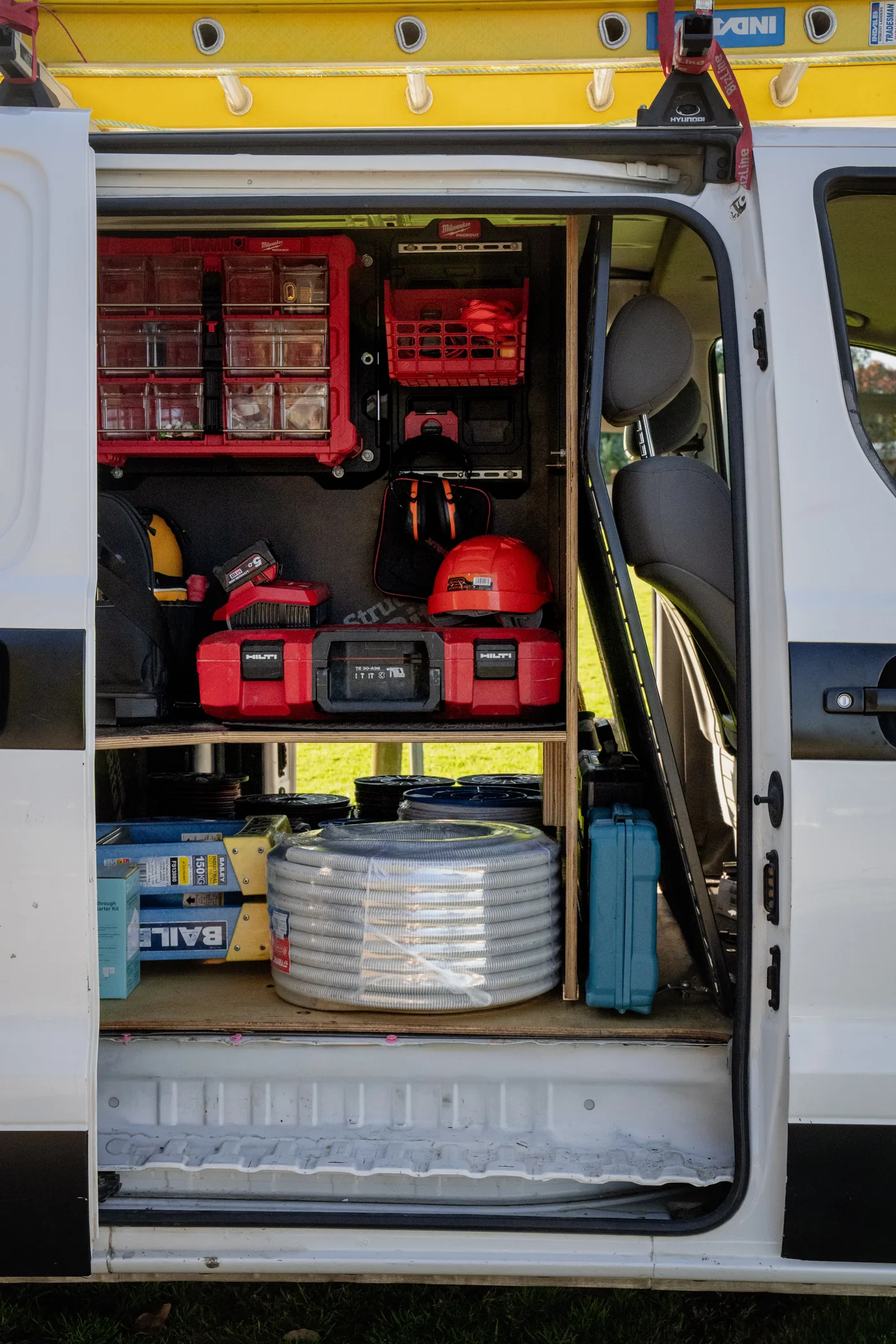 Drawer unit fitted beneath shelving at the side door of a van